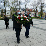 Na zdjęciu widoczna jest Delegacja niosąca kwiaty z okazji święta uchwalenia Konstytucji 3 Maja. W tle widoczny jest park. Delegacja składa się z dwóch męzczyzn.