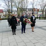 Na zdjęciu widoczna jest Delegacja niosąca kwiaty z okazji święta uchwalenia Konstytucji 3 Maja. W tle widoczny jest park. Delegacja składa się z dwóch kobiet i jednego mężczyzny.