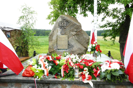 Na zdjęciu widoczny jest pomnik usytuowany w Jeziorach, upamiętniający walkę stoczoną przez polskich partyzantów z 34 pułku piechoty Armii Krajowej z Niemcami w czasie II wojny światowej. Pod nim zostały złożone kwiaty i zapalone znicze.