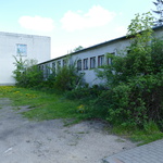 Zdjęcie przedstawia stary budynek szkoły od wewnętrznej strony podwórka. Przy ścianach rosną liczne krzewy. Budynek ma wiele okien.