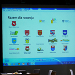 Zdjęcie przedstawia slajd prezentacji, na której znajdują się herby i logotypy wszystkich wchodzących w skład partnerstwa gmin.